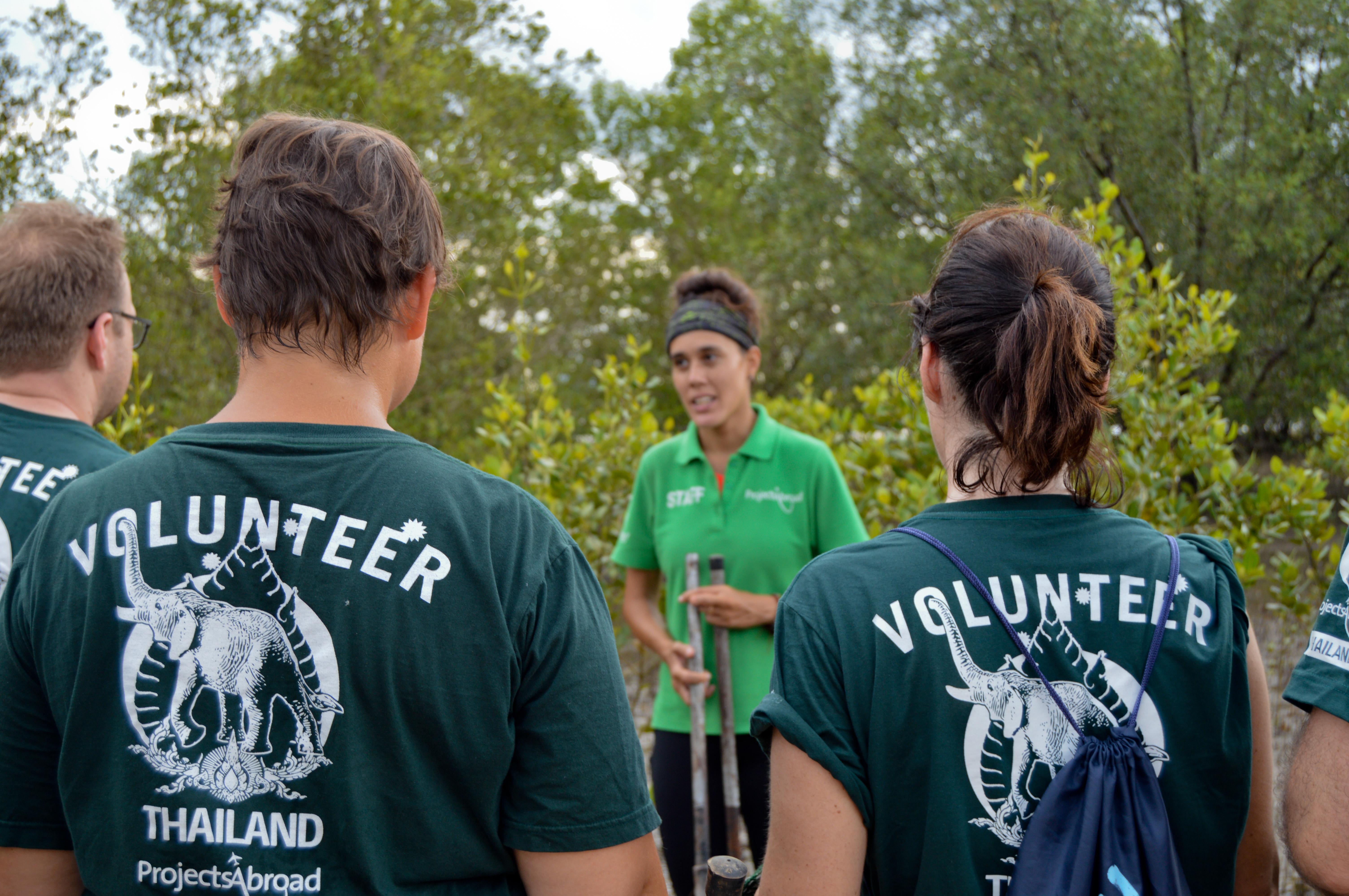 A Projects Abroad staff member guides volunteers during one of our wildlife conservation volunteer opportunities. A group of Projects Abroad Conservation volunteers listen to a staff member explain an activity outdoors at their project.
